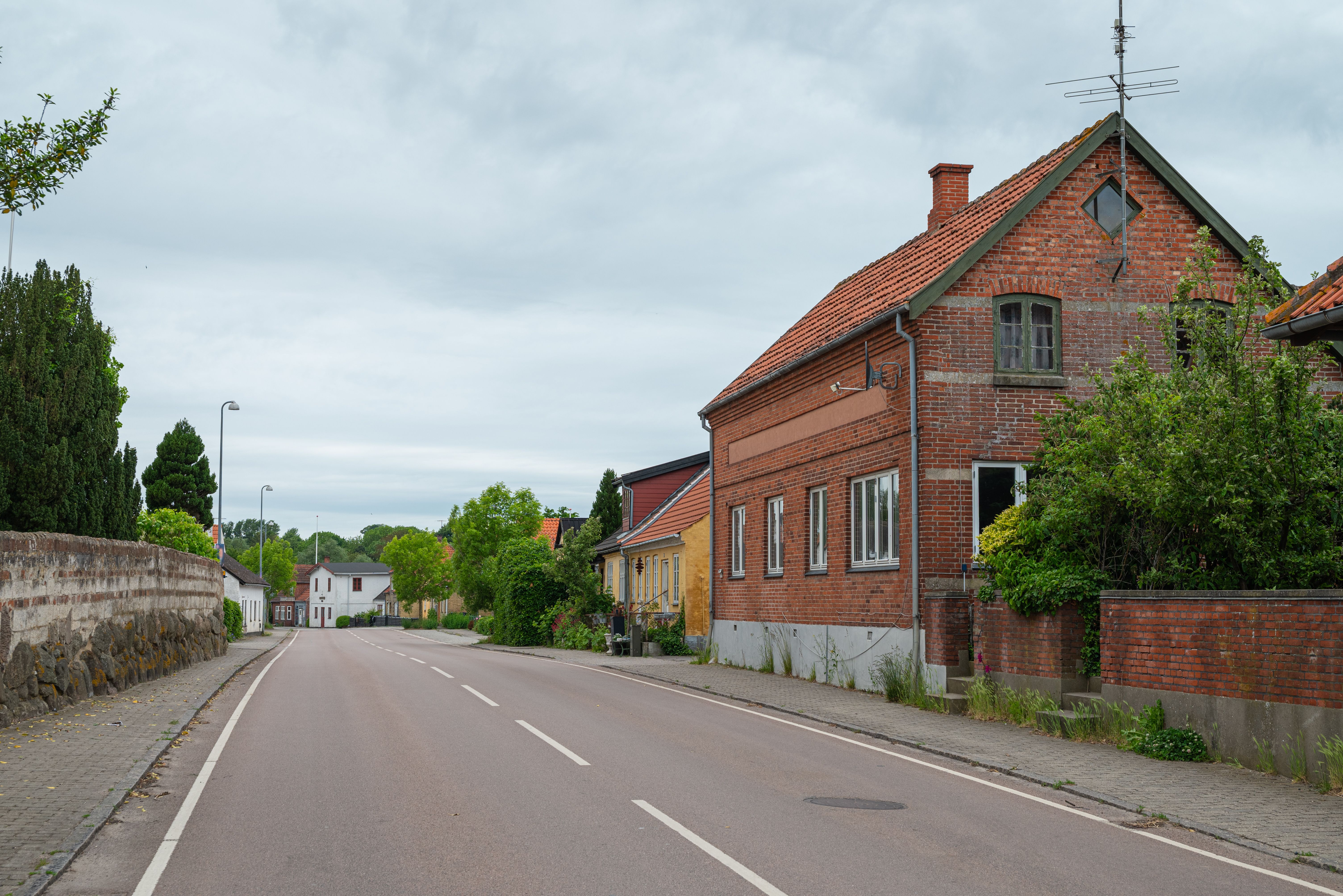Die kleine Ortschaft Borre zeigt typische dänische Dorfarchitektur mit roten Backsteingebäuden entlang einer ruhigen Dorfstraße.