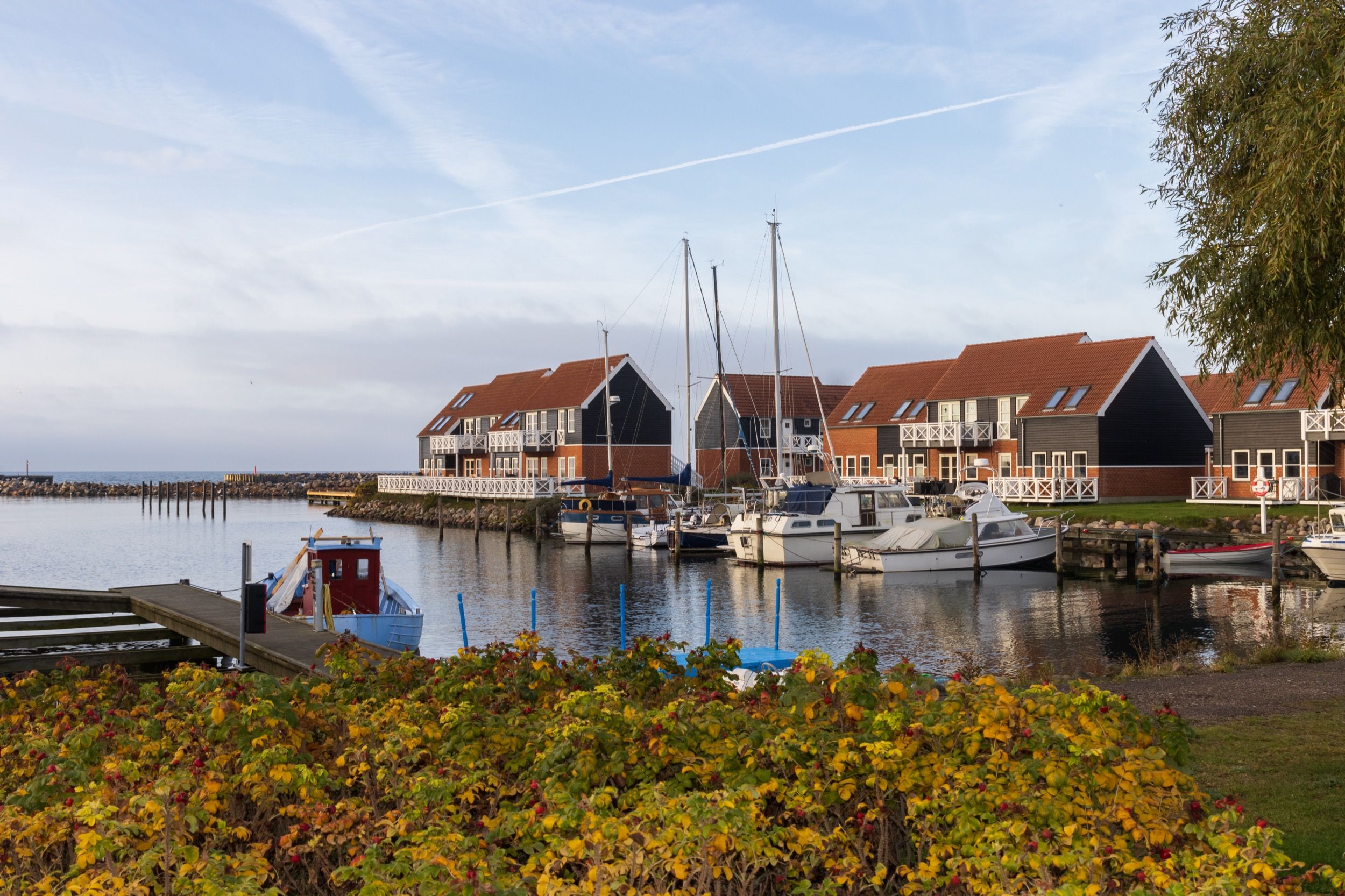 Klintholm Havn mit Segelbooten und modernem Resort-Gebäude in Herbstlicht.