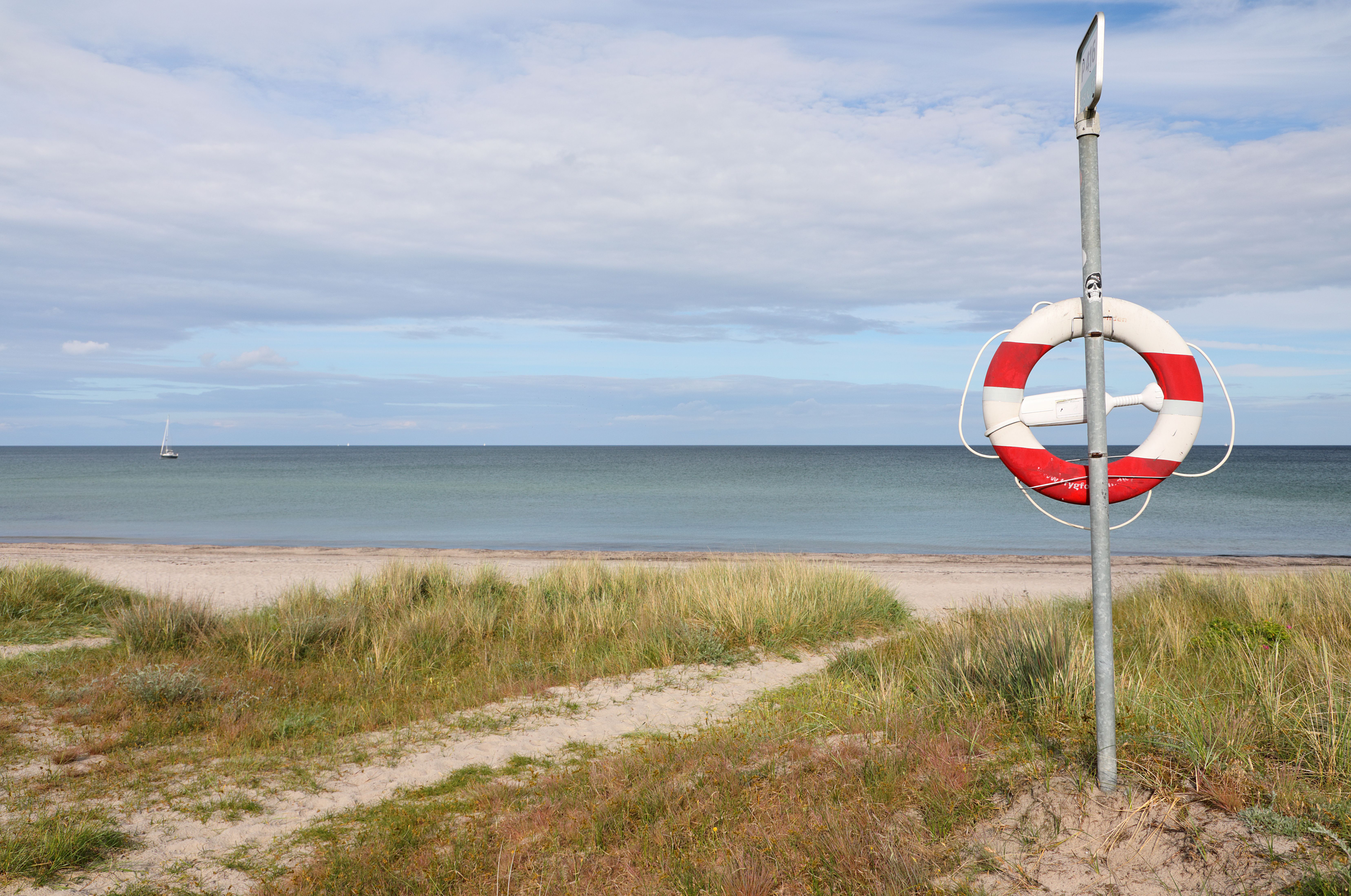 Der Sandstrand Marielyst an der Ostsee mit Rettungsring zeigt eine der beliebten Badestellen auf Møn, ideal für einen entspannten Strandtag.