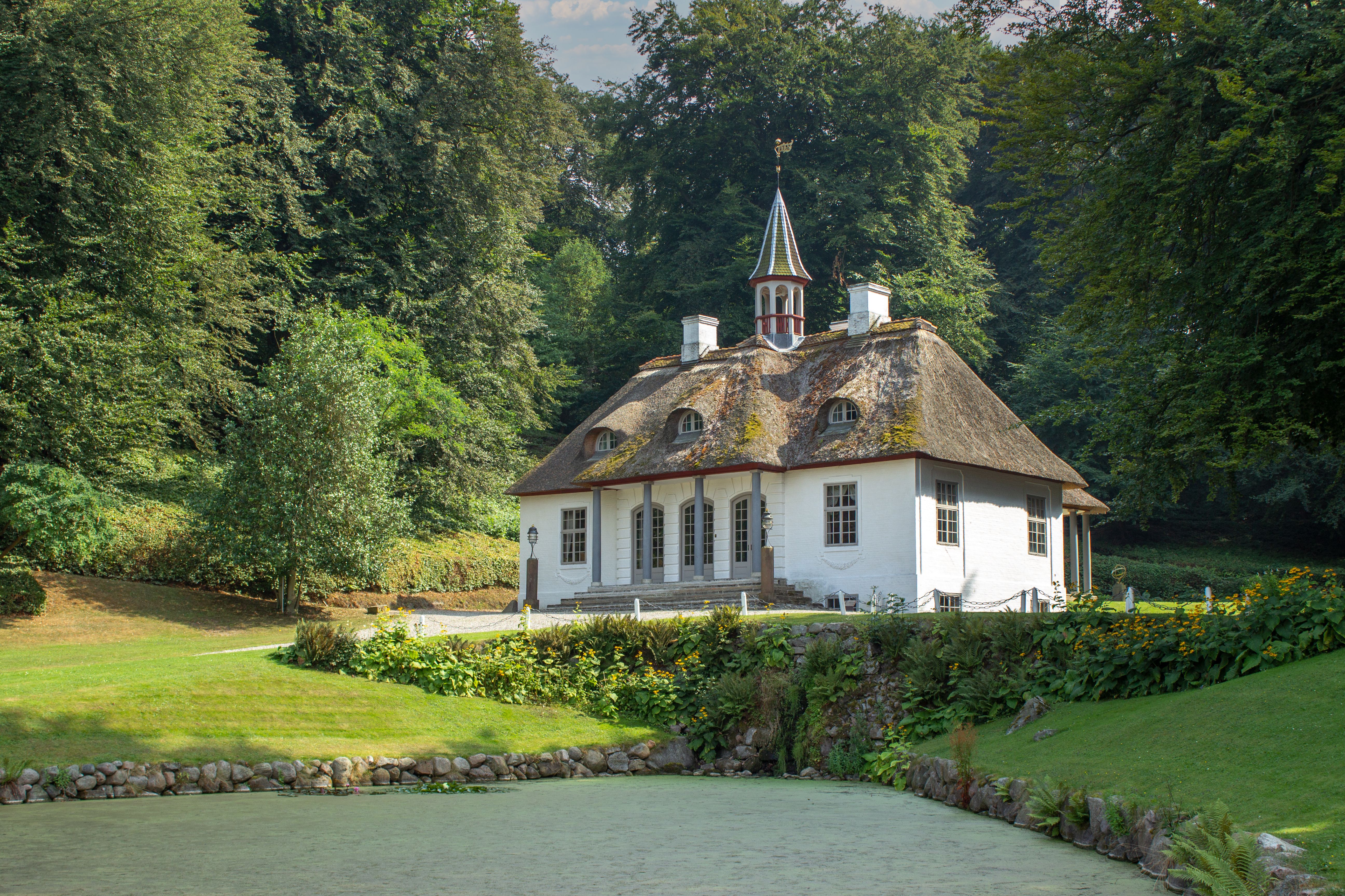 Das charmante Gärtnerhaus mit Strohdach im Liselund-Park zeigt die romantische Parklandschaft des dänischen Schlossgeländes.
