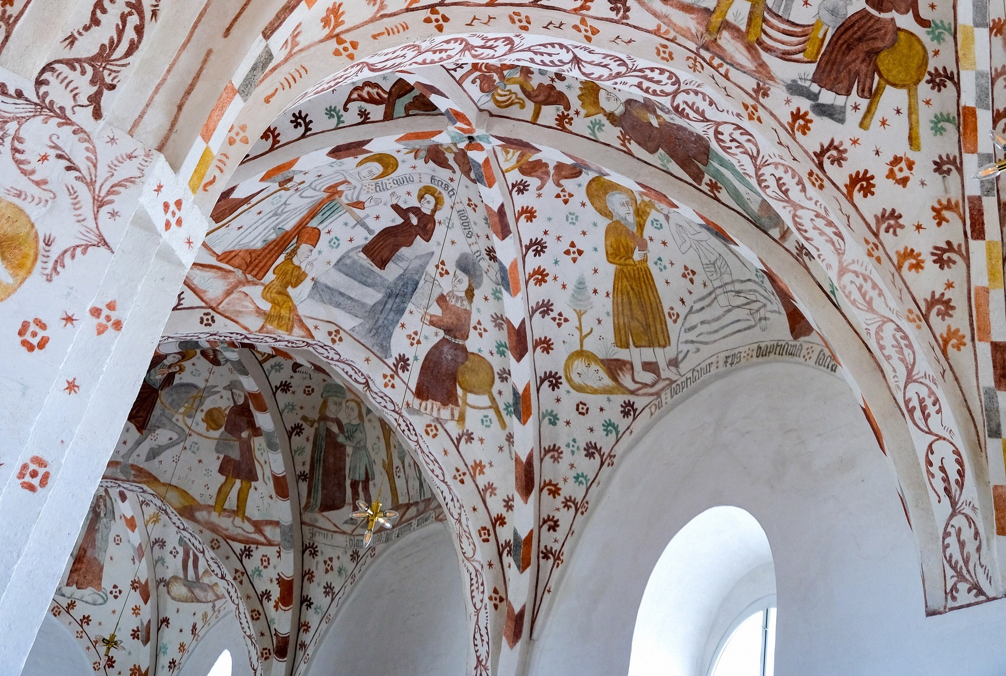 Medieval frescoes by the Elmelunde Master in the vault, showing biblical scenes and vines